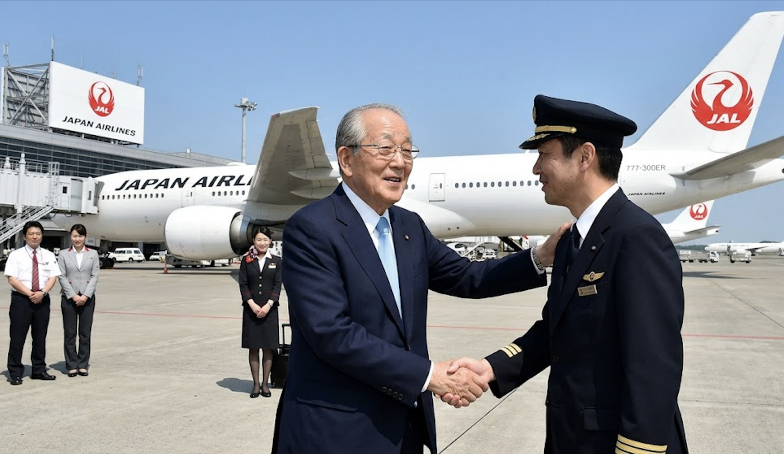 Kazuo Inamori shaking hands with a Japan Airlines pilot in front of a JAL aircraft during the company's turnaround